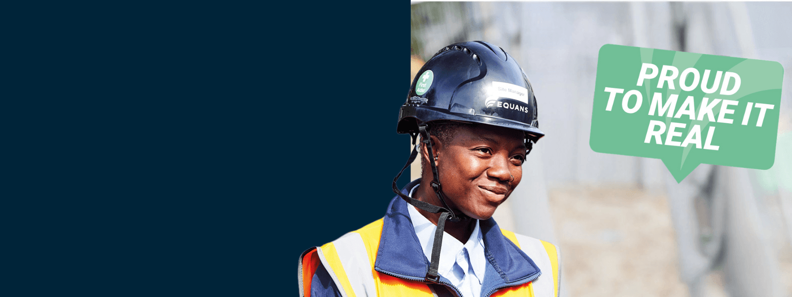 Equans engineer in a hard hat and hi-vis jacket beside a 'Proud to make it real' sign
