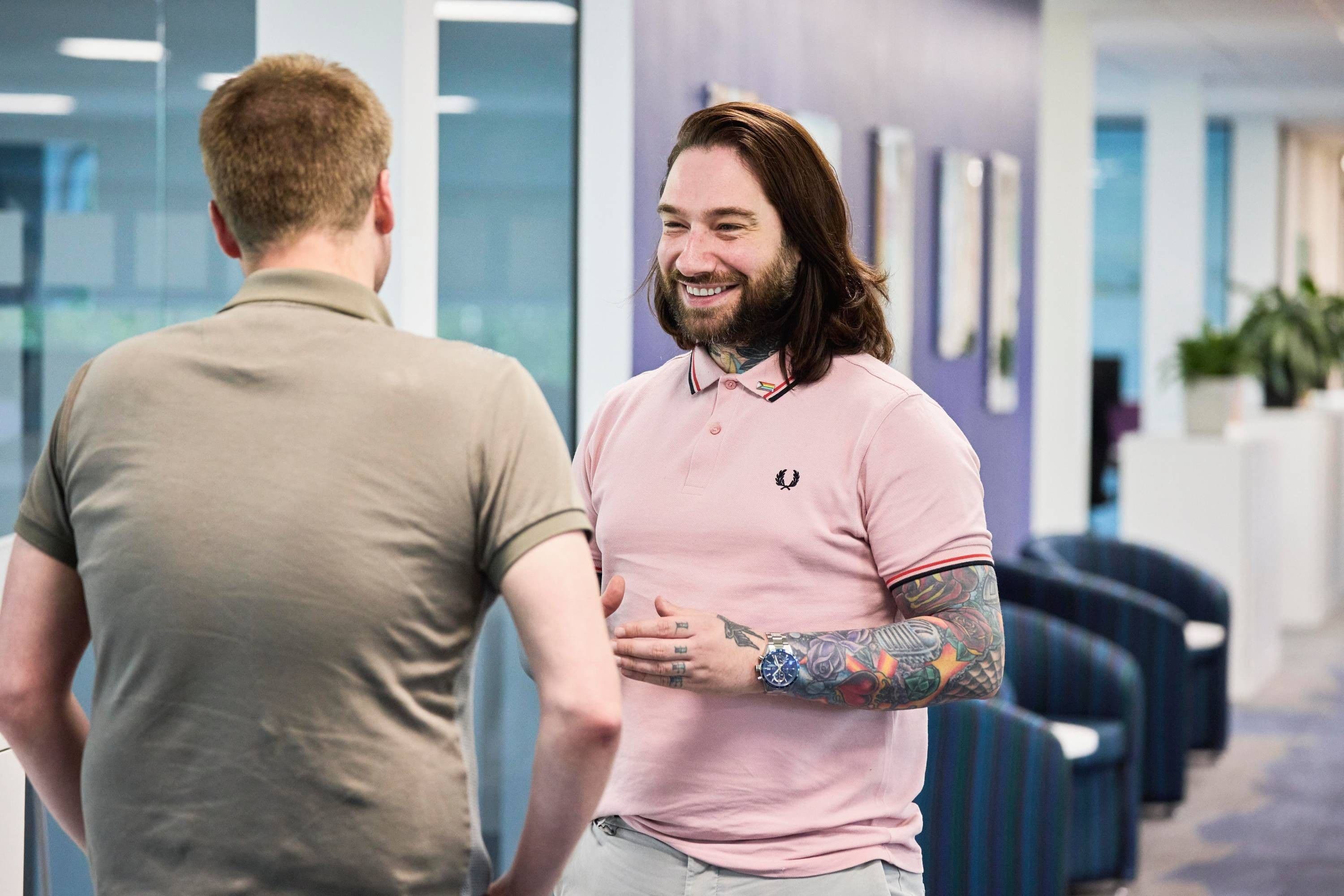 Two Equans colleagues talking in an open-plan office