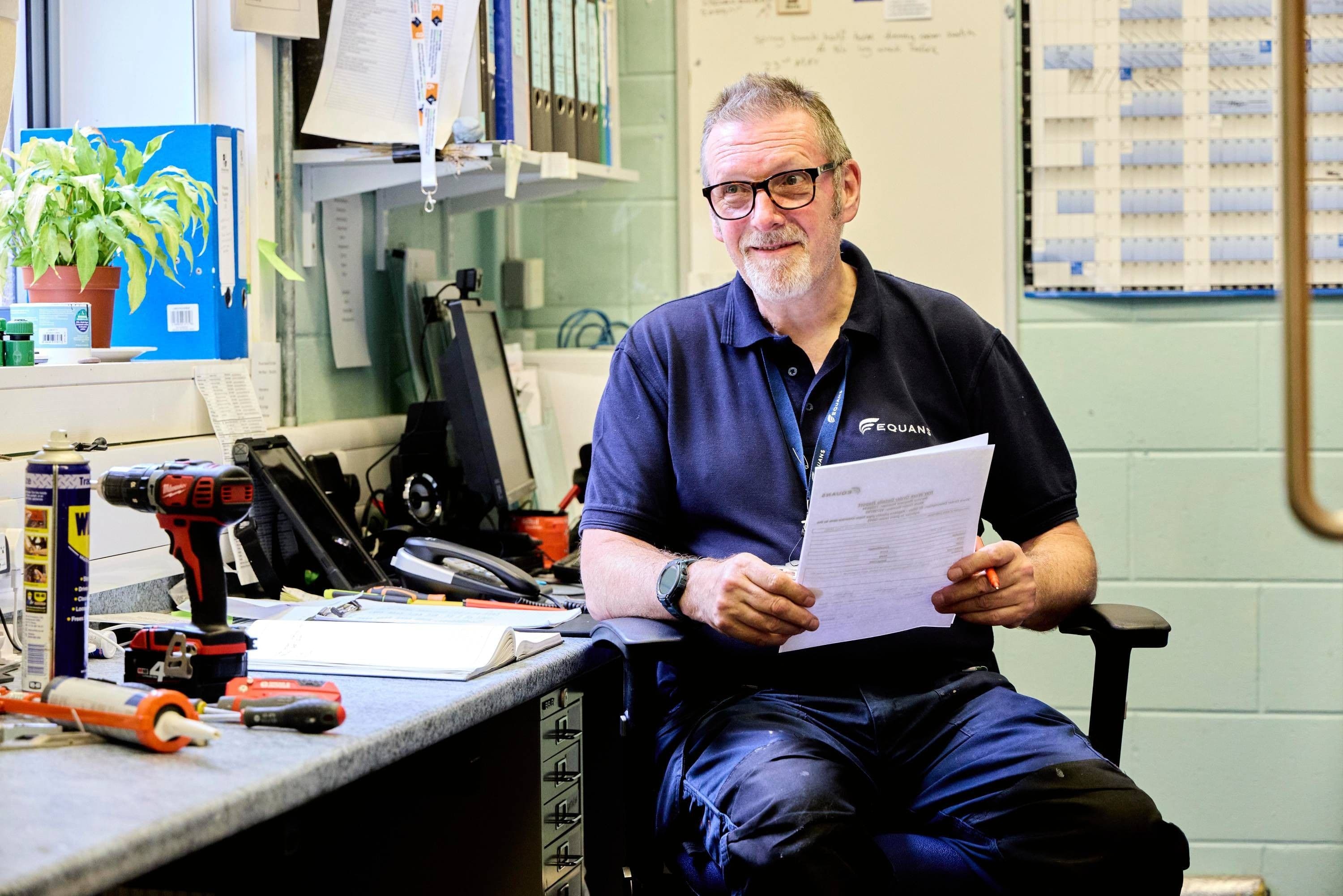 Equans site manager reviewing paperwork at a workshop desk