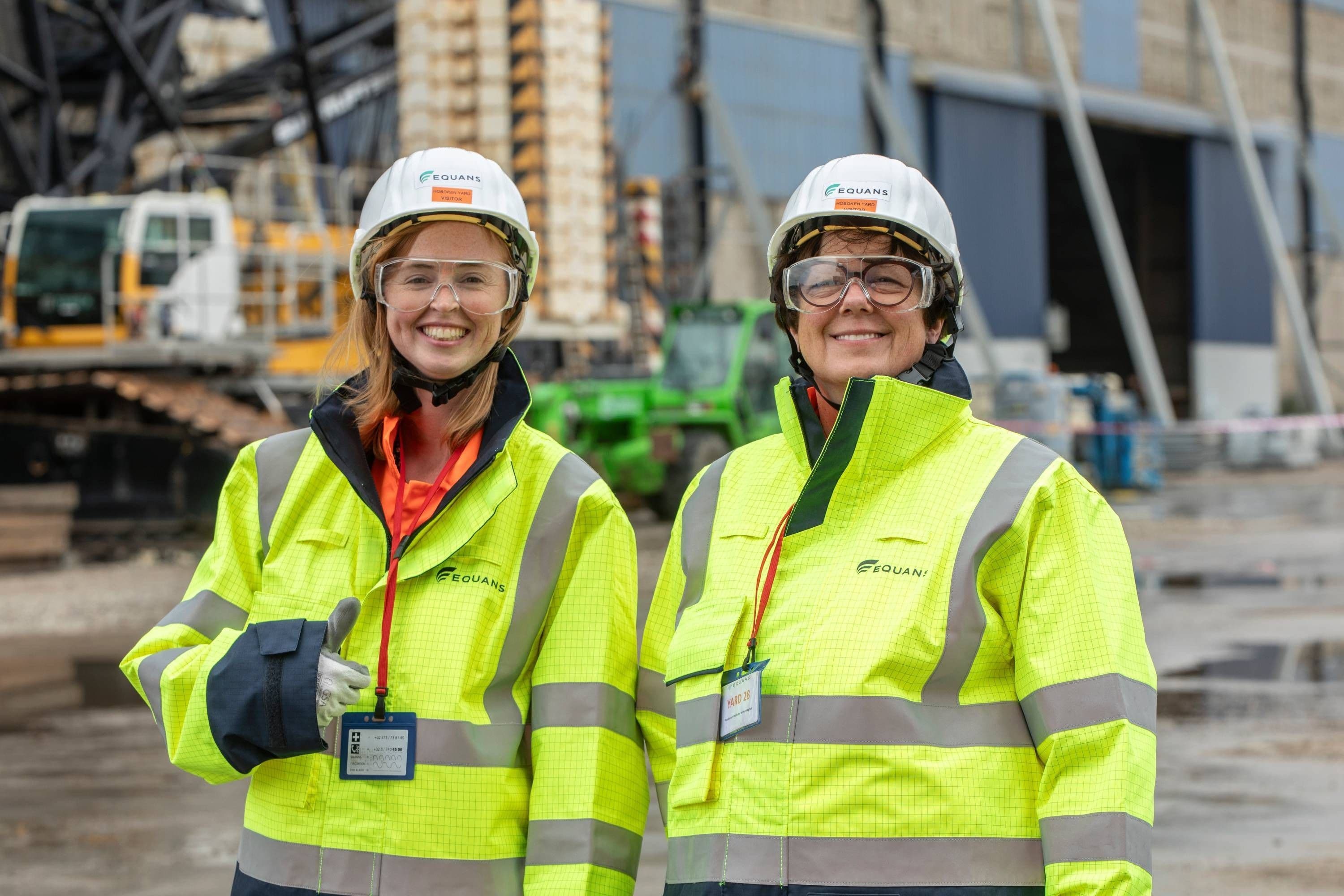 Two Equans colleagues in yellow hi-vis smiling on a construction site